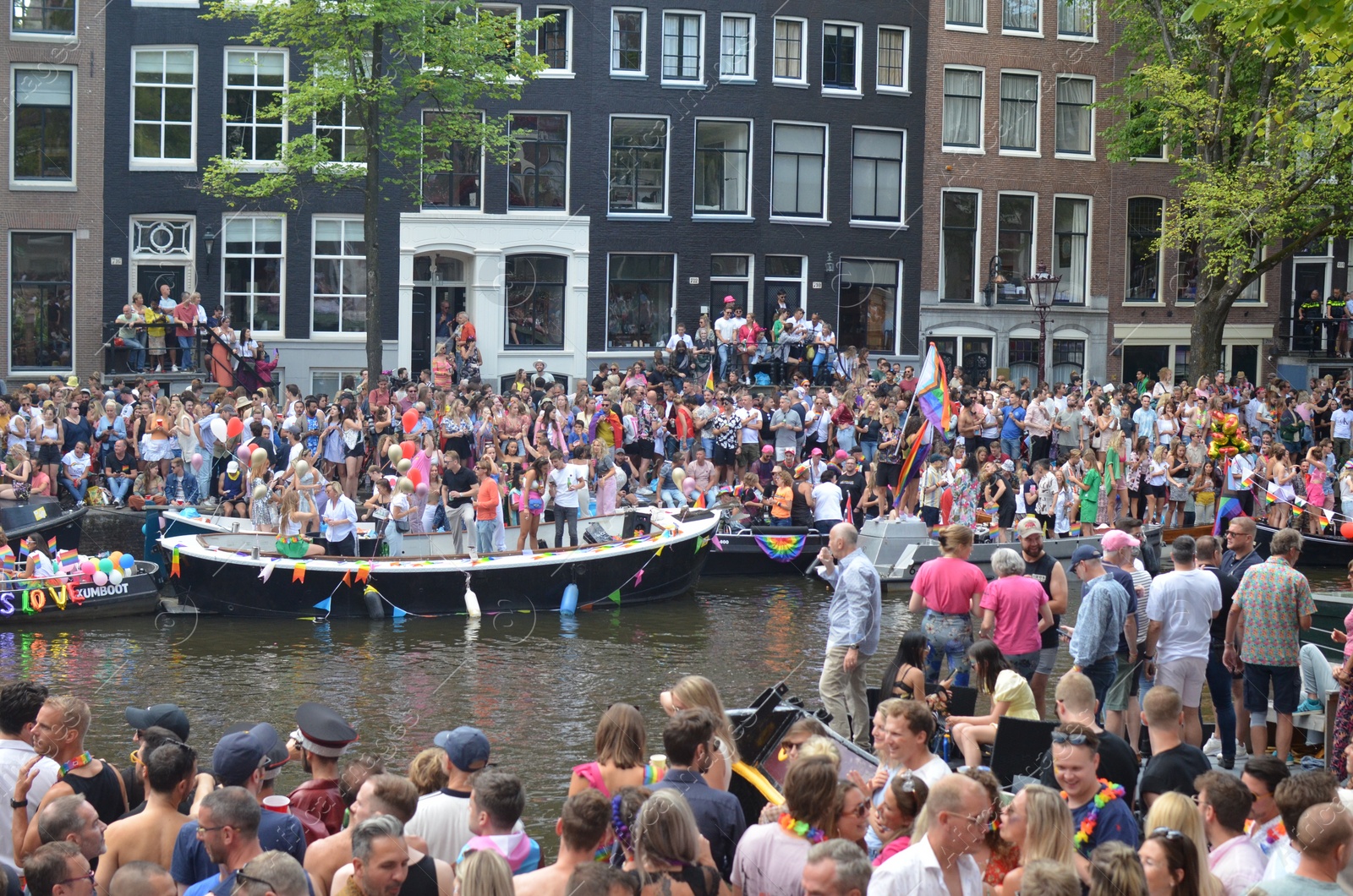 Photo of AMSTERDAM, NETHERLANDS - AUGUST 06, 2022: Many people in boats at LGBT pride parade on river