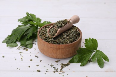 Photo of Dried aromatic parsley and fresh leaves on white wooden table