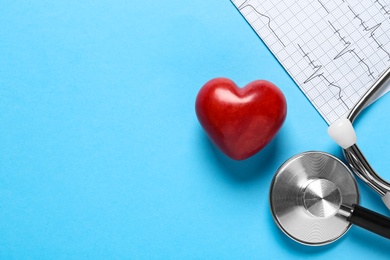 Photo of Cardiogram report, red decorative heart and stethoscope on light blue background, flat lay with space for text