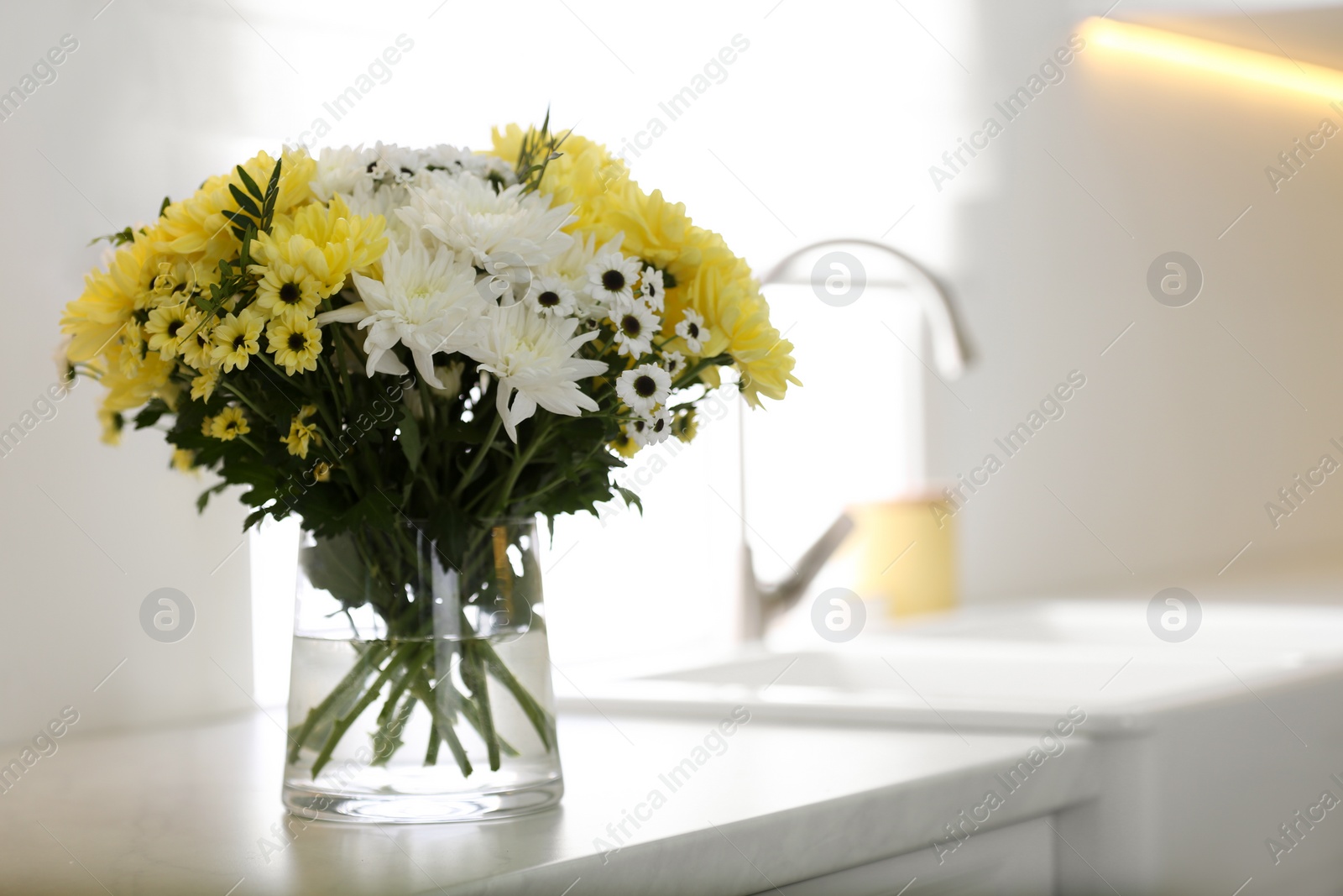 Photo of Vase with beautiful chrysanthemum flowers on countertop in kitchen, space for text. Interior design