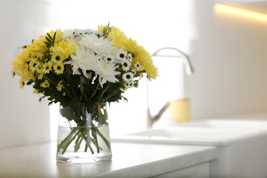 Vase with beautiful chrysanthemum flowers on countertop in kitchen, space for text. Interior design