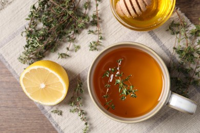 Photo of Aromatic herbal tea with thyme, honey and lemon on wooden table, top view