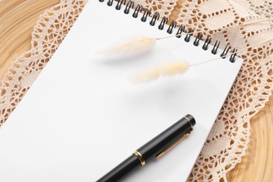 Guest list. Notebook, pen, spikelets and lace ribbon on wooden background, above view