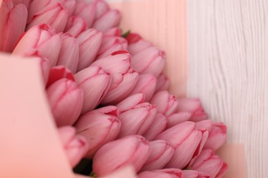 Bouquet of beautiful pink tulips on white wooden table, above view