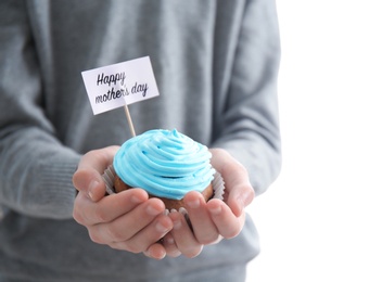 Photo of Little child holding tasty cupcake for Mother's Day, closeup