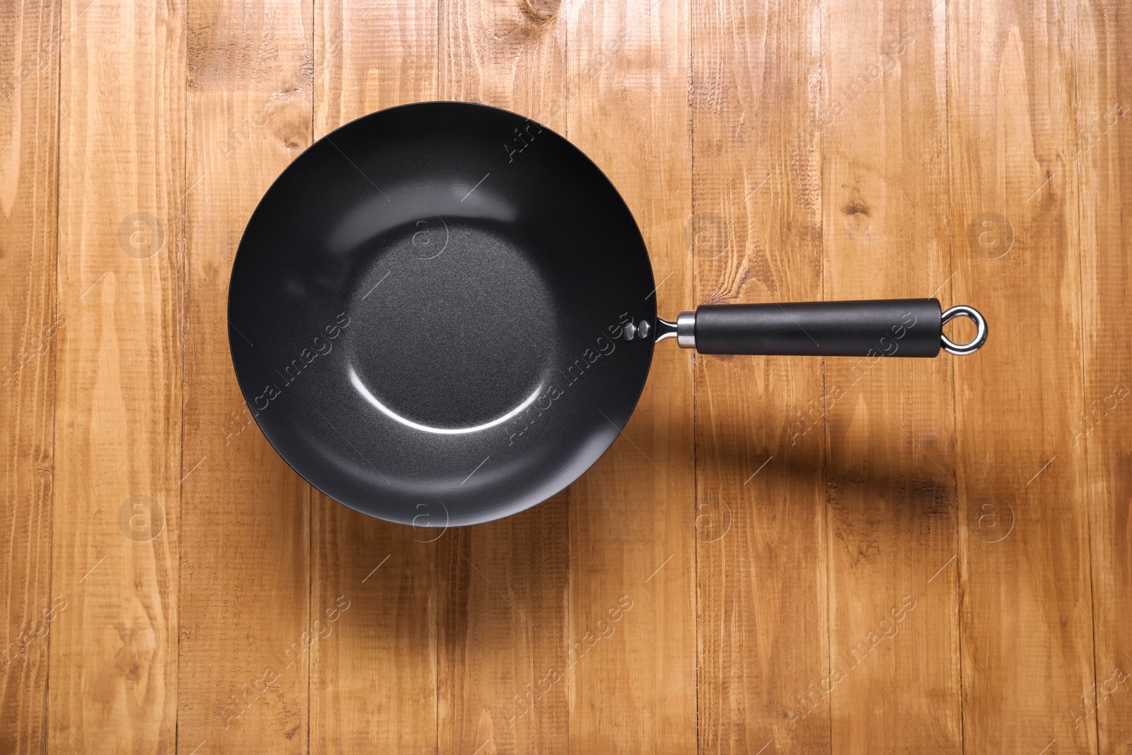 Photo of Empty iron wok on wooden table top view. Chinese cookware