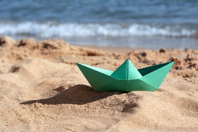 Photo of Green paper boat near sea on sunny day, space for text