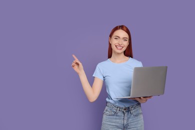 Smiling young woman with laptop on lilac background, space for text