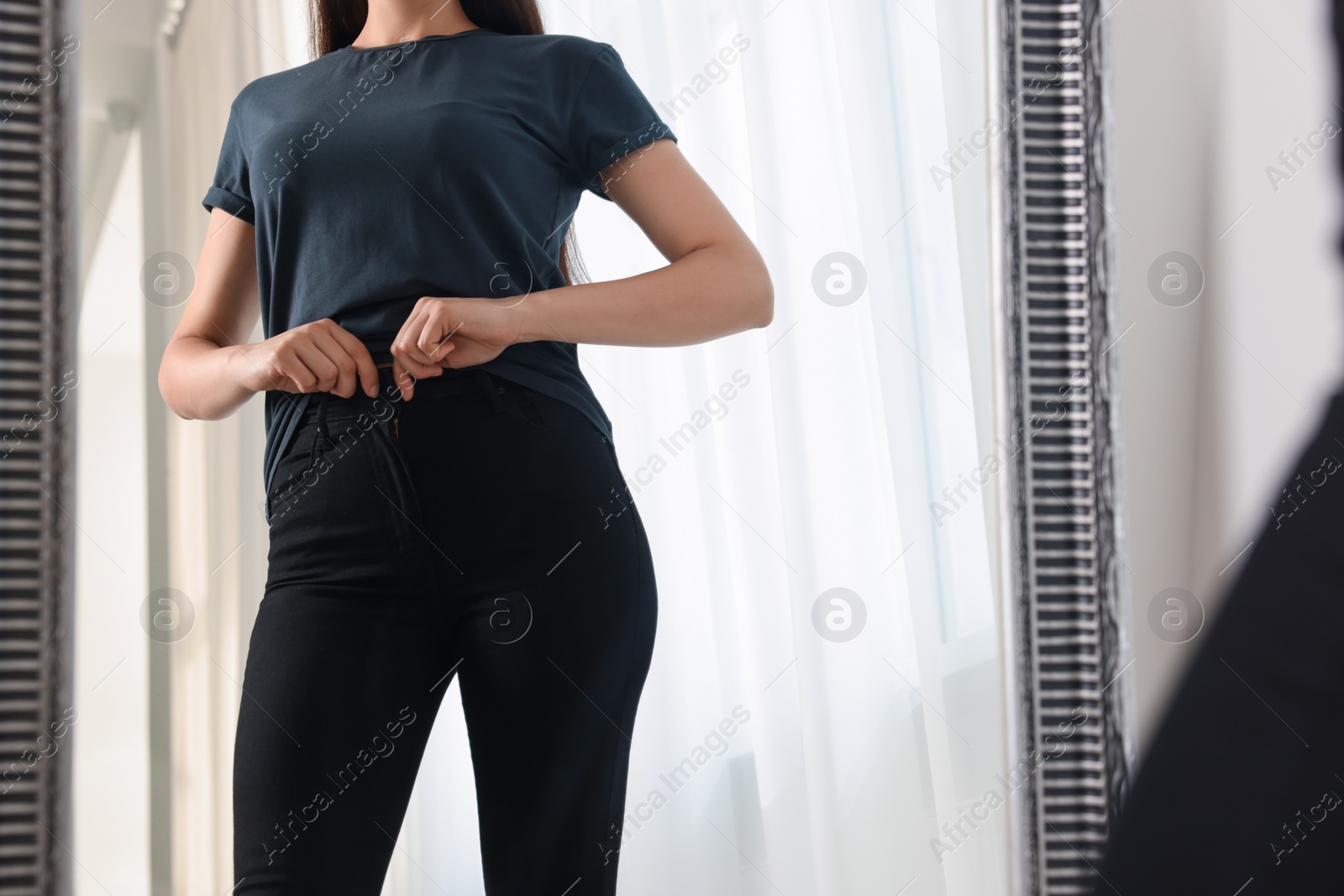 Photo of Woman in stylish black jeans near mirror indoors, closeup. Space for text