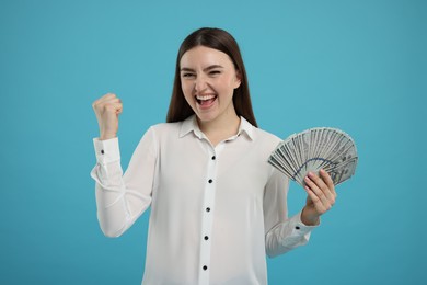 Photo of Excited woman with dollar banknotes on light blue background