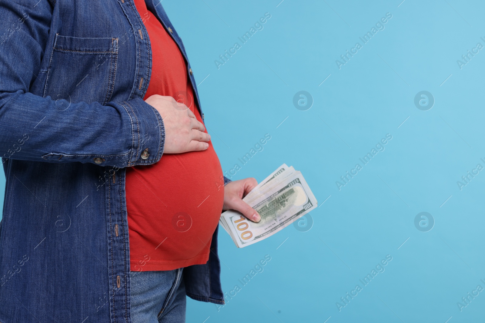 Photo of Surrogate mother. Pregnant woman with dollar banknotes on light blue background, closeup. Space for text