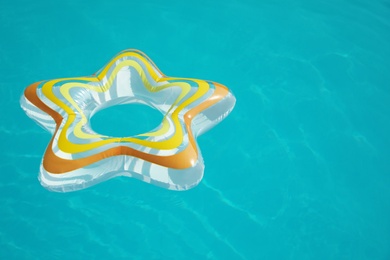 Photo of Star shaped inflatable ring floating in swimming pool on sunny day. Space for text