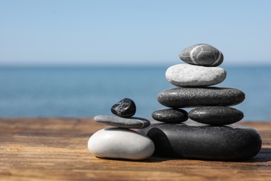 Photo of Stacks of stones on wooden pier near sea, space for text. Zen concept