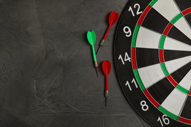 Dart board with color arrows on grey stone background, top view. Space for text