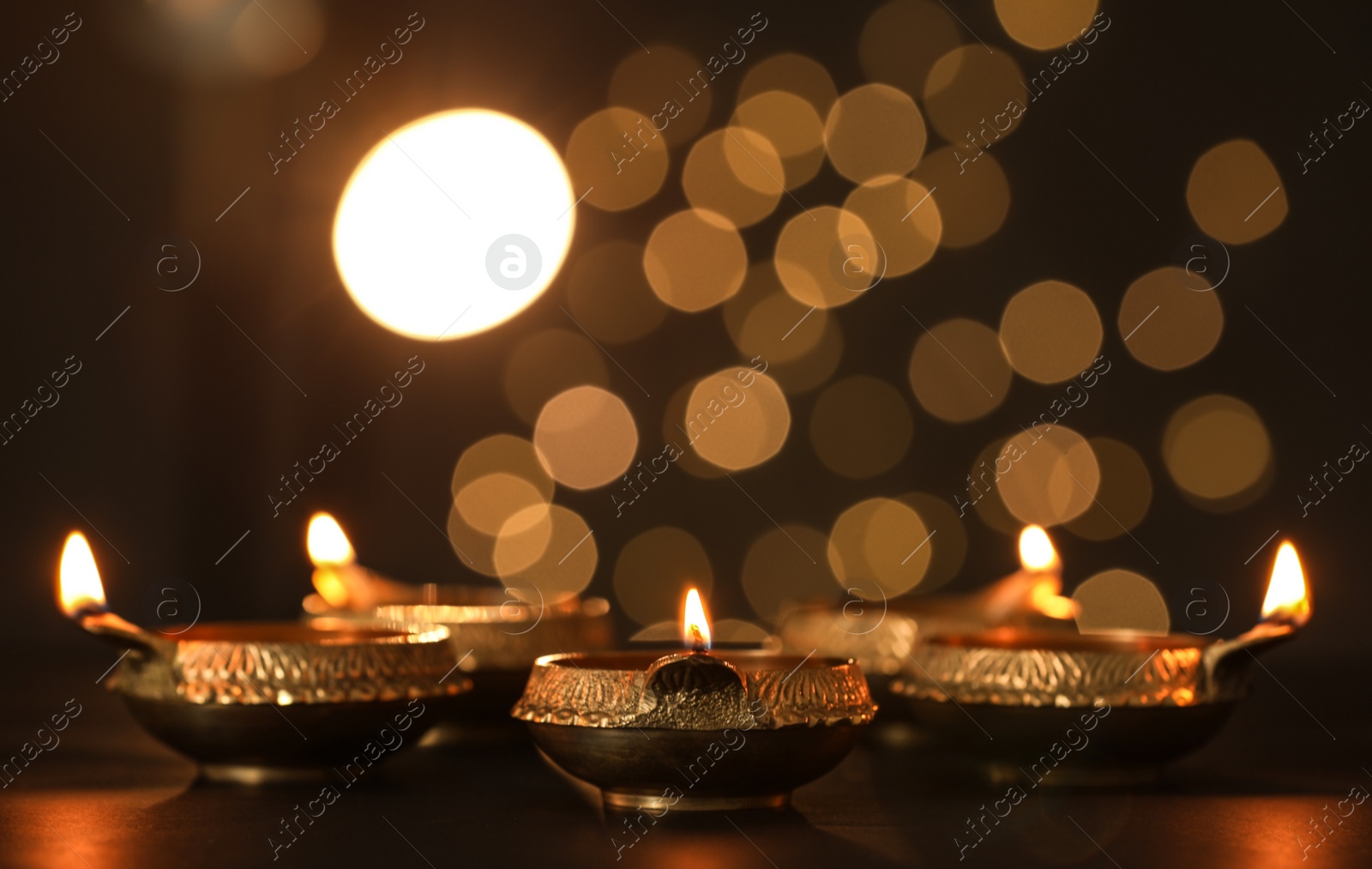 Photo of Lit diya lamps on dark table. Diwali celebration