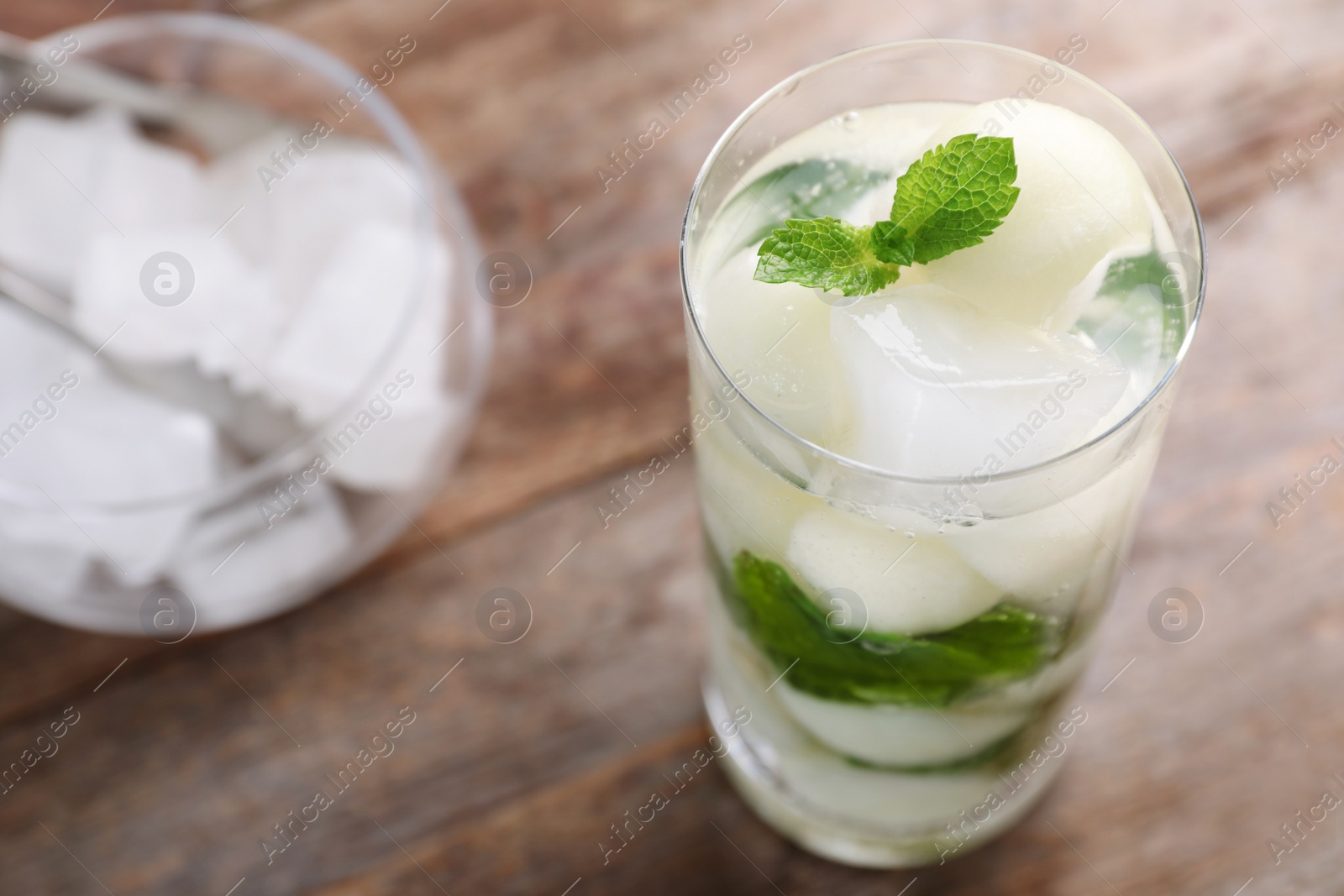 Photo of Glass with tasty melon ball drink on wooden table