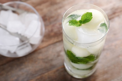 Glass with tasty melon ball drink on wooden table