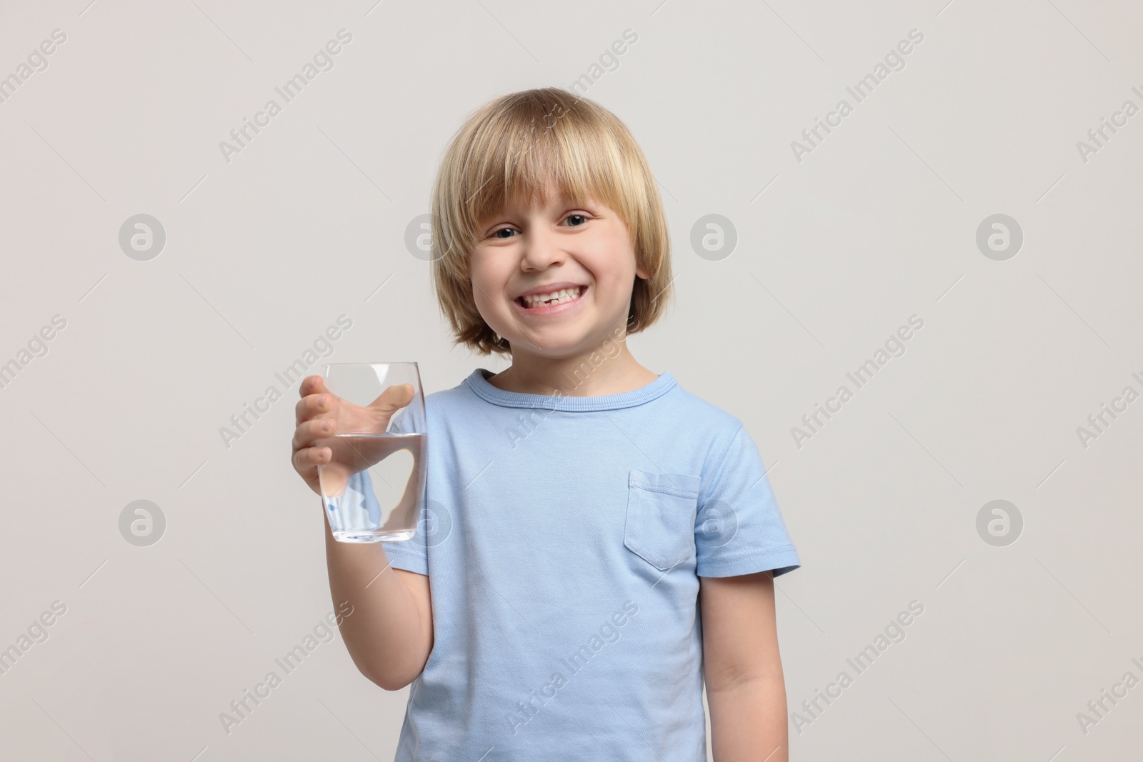 Photo of Happy little boy holding glass of fresh water on white background