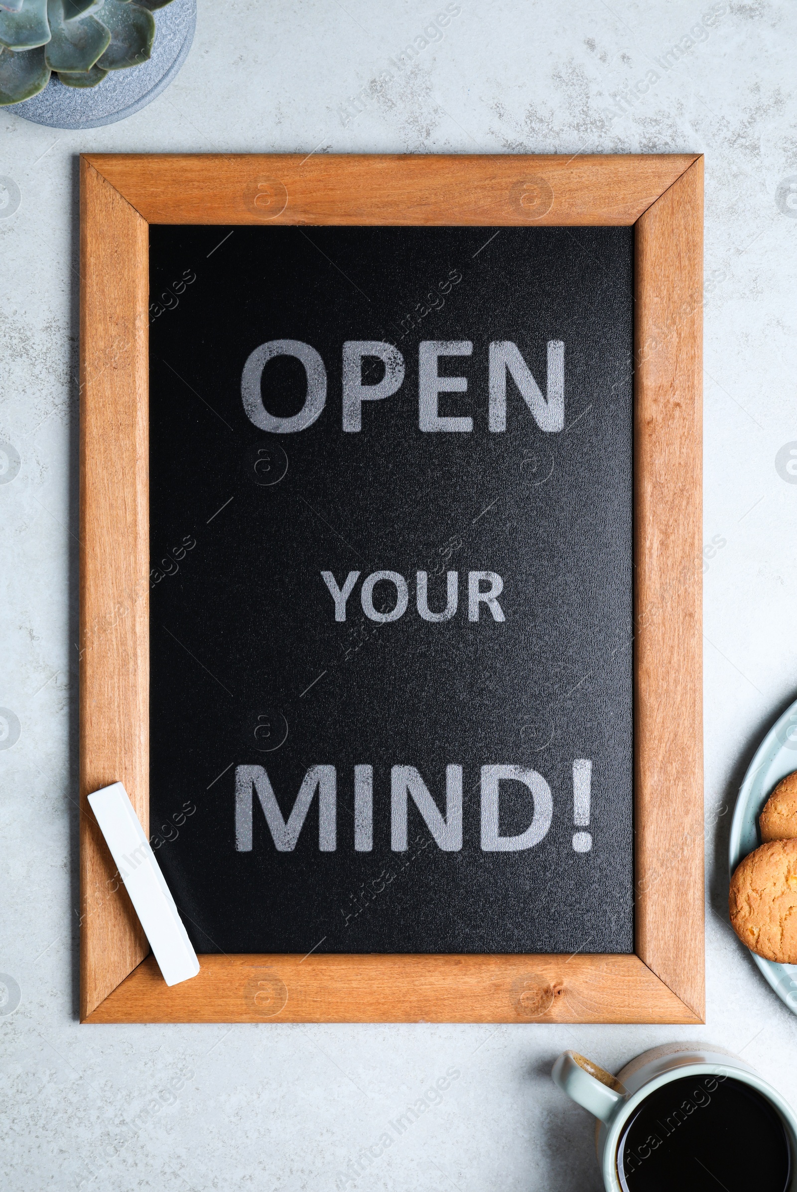 Image of Small chalkboard with motivational quote Open your mind, coffee and cookies on light grey table, flat lay