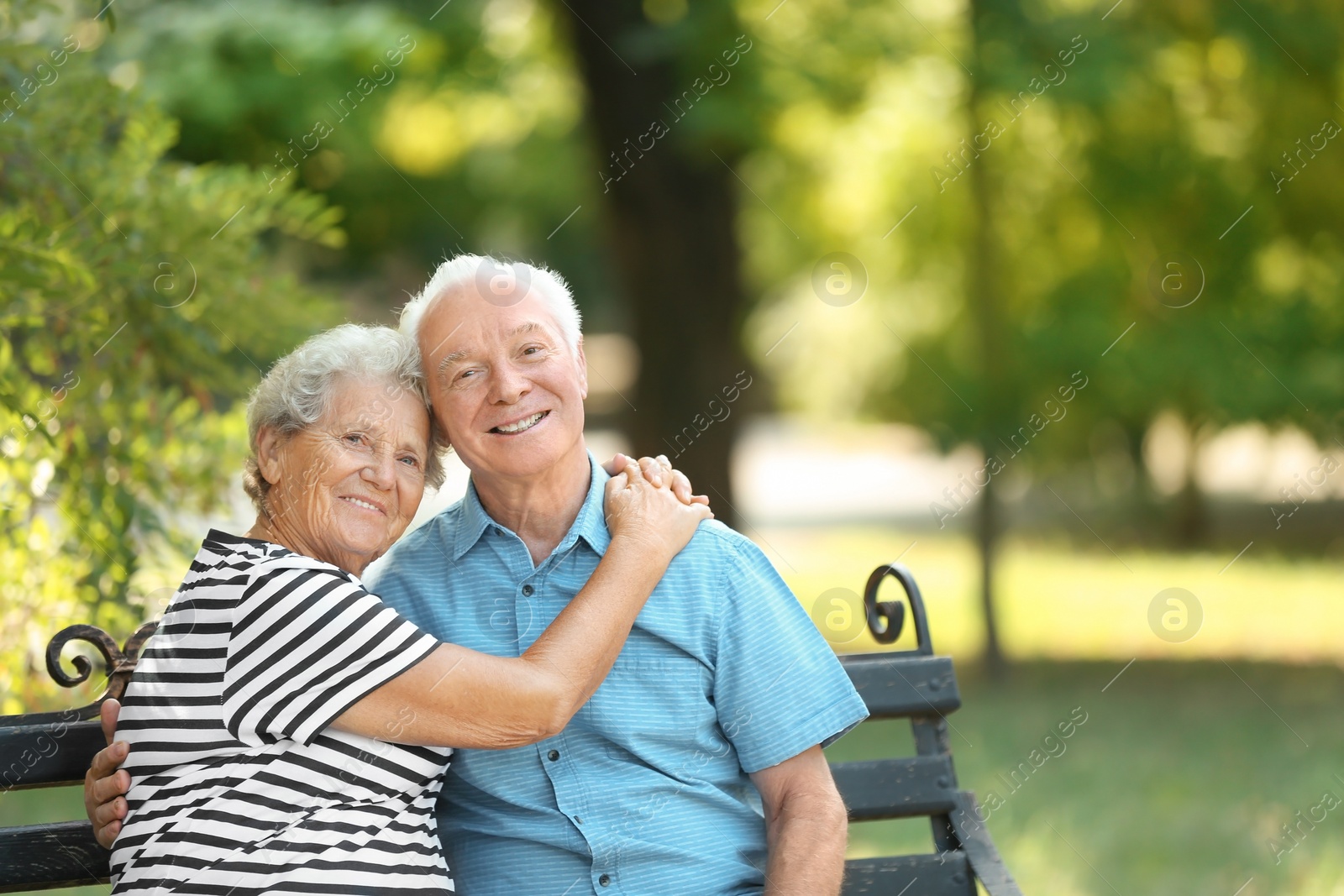 Photo of Elderly couple resting on bench in park