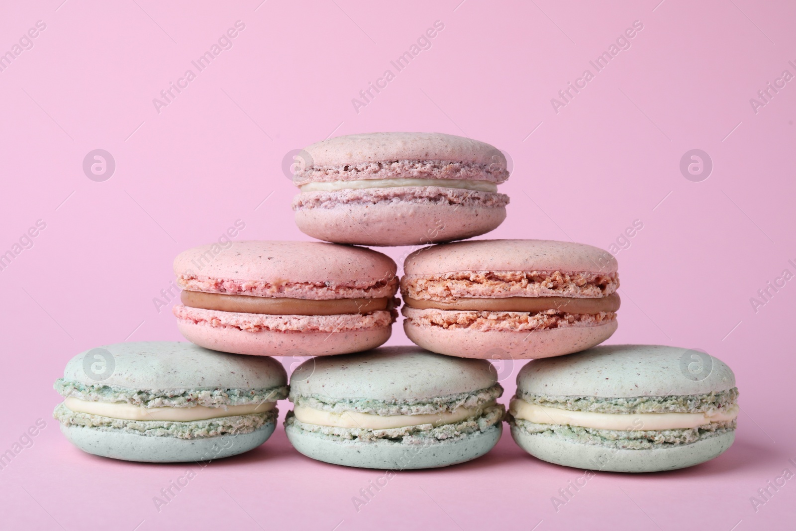 Photo of Pile of delicious colorful macarons on pink background