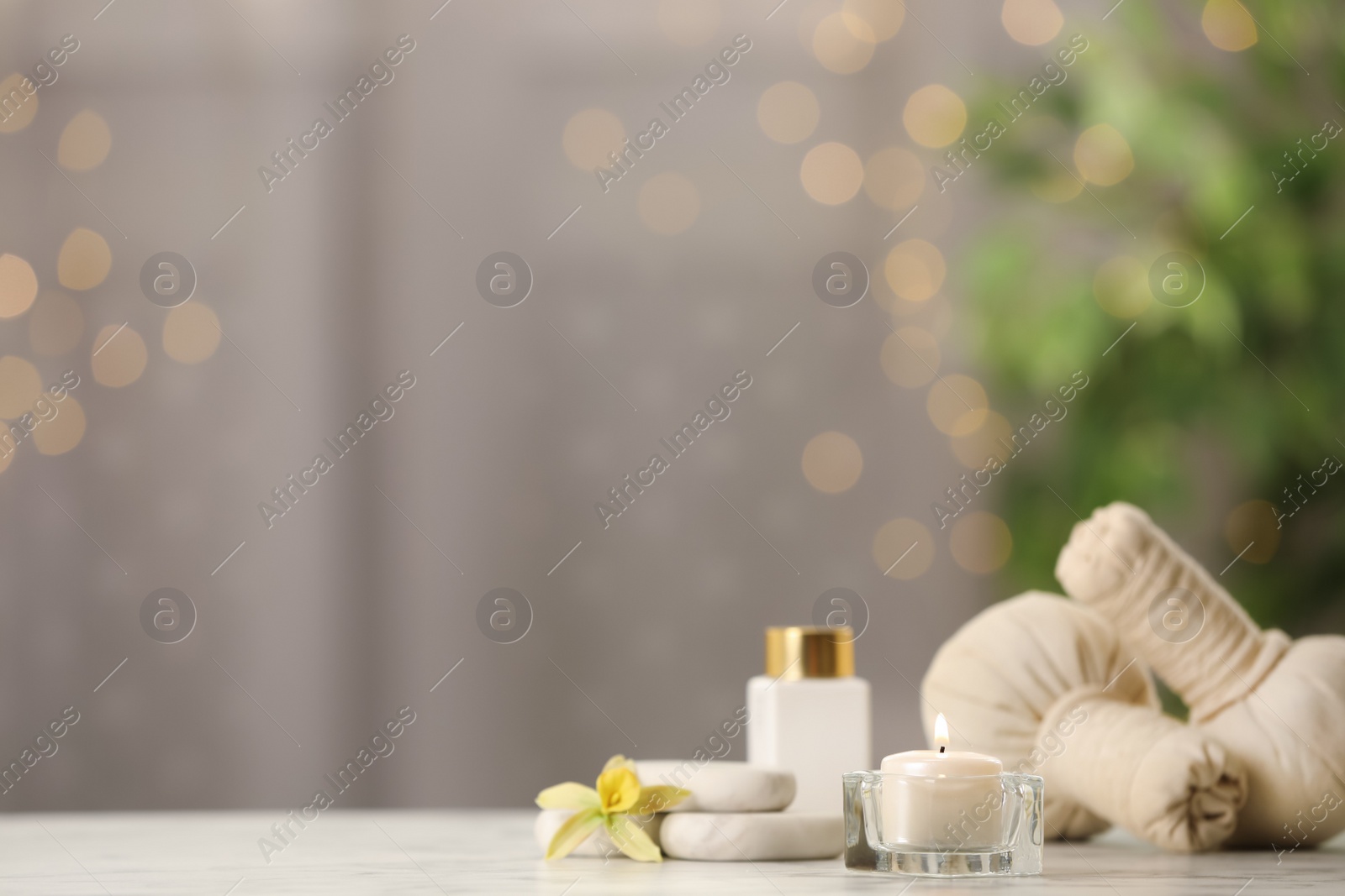 Photo of Composition with herbal bags and burning candle on white table against blurred festive lights, space for text