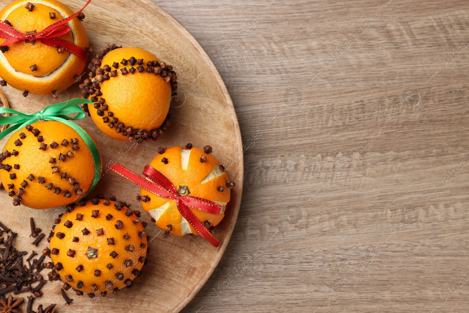 Photo of Pomander balls made of tangerines with cloves on wooden table, top view. Space for text