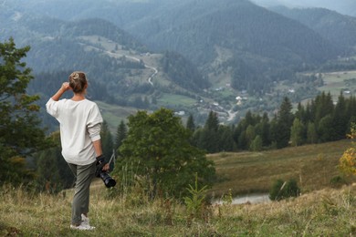 Photo of Photographer with modern professional camera in mountains, back view