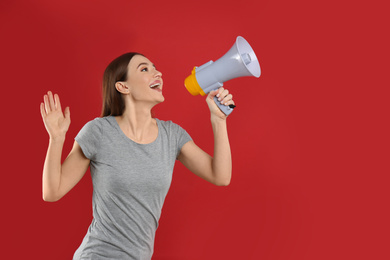 Photo of Young woman with megaphone on red background. Space for text