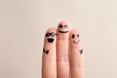 Photo of Fingers with drawings of happy faces against light background. Unity concept