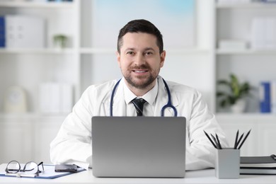 Doctor with laptop at table in clinic. Online consultation