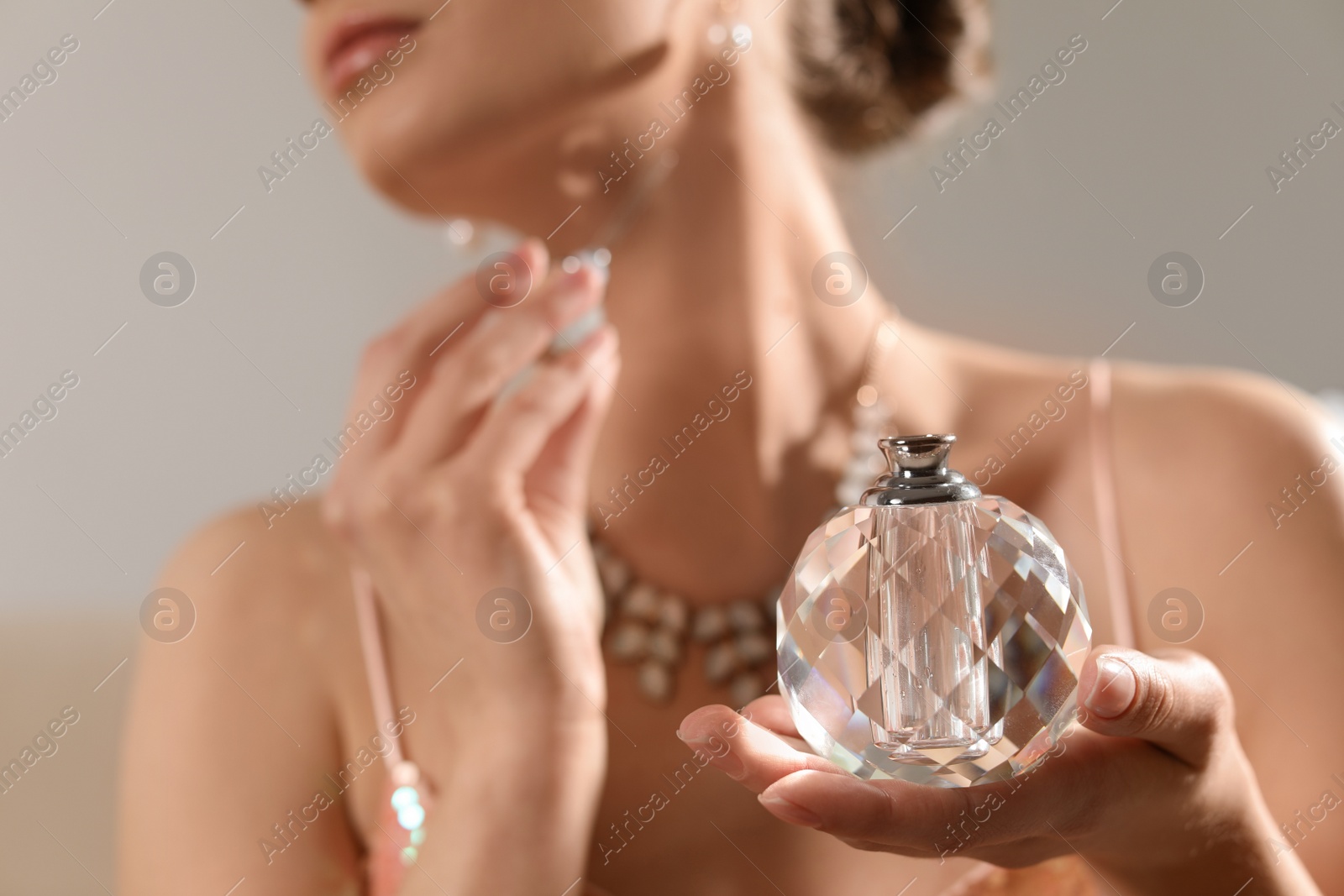 Photo of Young woman applying perfume on blurred background, closeup