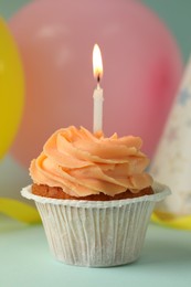 Photo of Tasty birthday cupcake with candle on light blue table, closeup