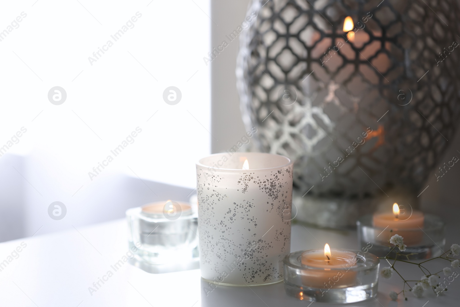 Photo of Beautiful burning candles on table at home. Space for text