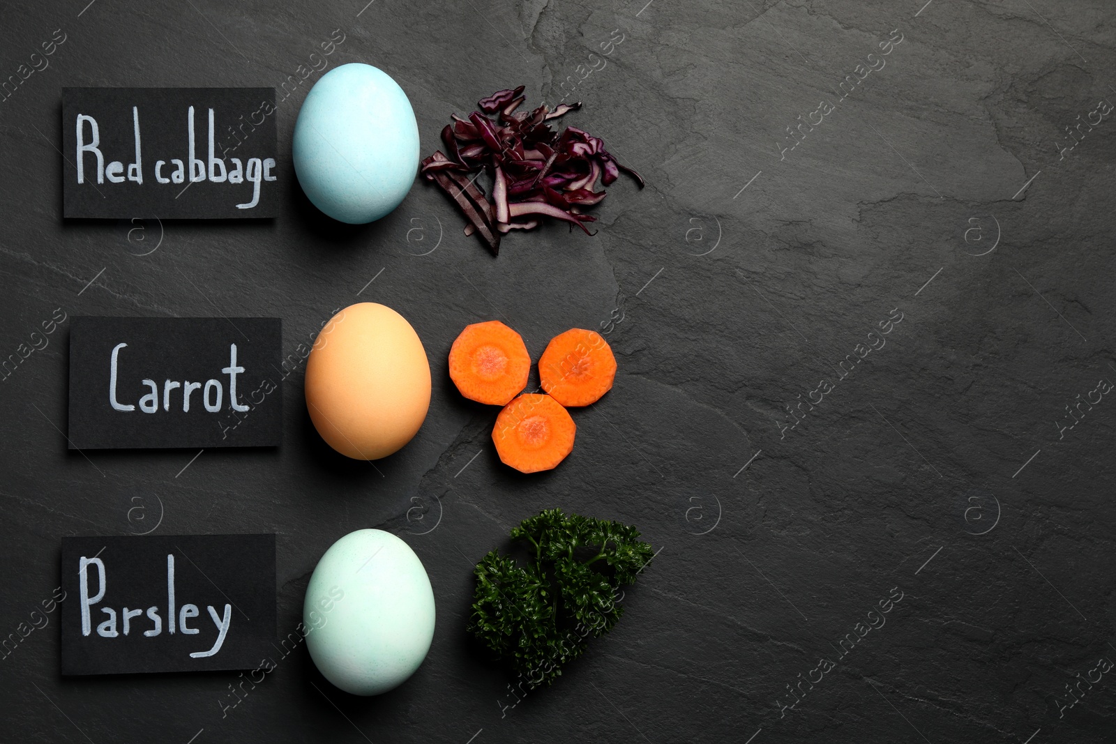 Photo of Naturally painted Easter eggs and space for text on black table, flat lay. Red cabbage, carrot, parsley used for coloring