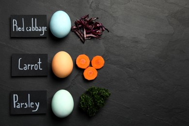 Naturally painted Easter eggs and space for text on black table, flat lay. Red cabbage, carrot, parsley used for coloring