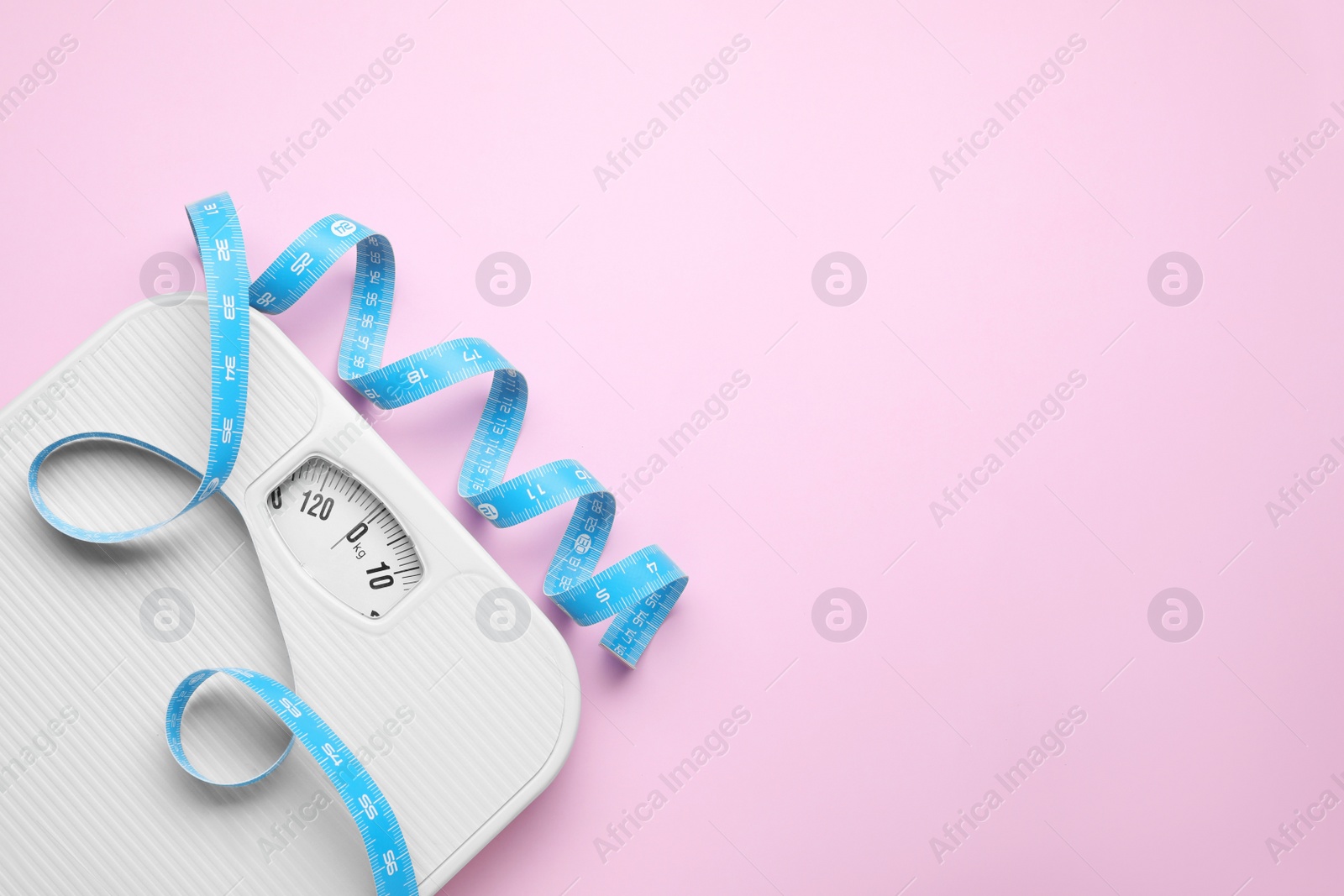 Photo of Scales and measuring tape on pink background, top view. Space for text