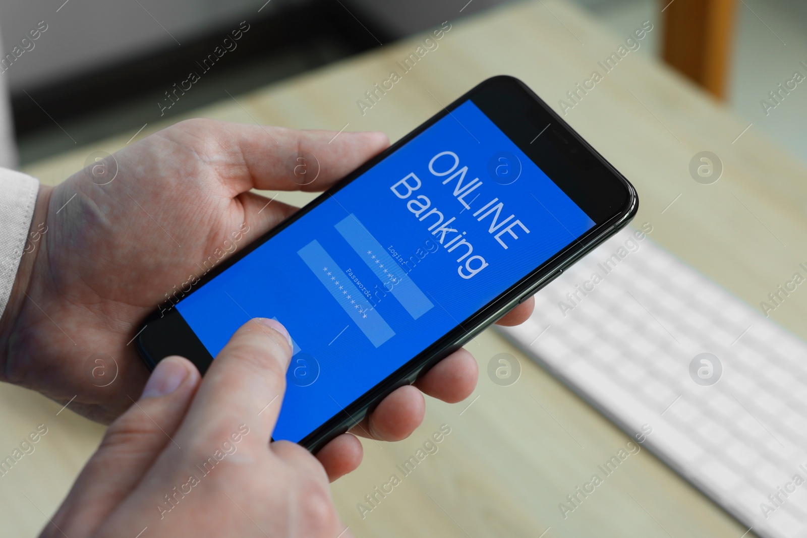 Photo of Man using online banking app on smartphone at wooden office table, closeup