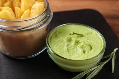 Photo of Serving board with french fries, guacamole dip and rosemary on wooden table, closeup