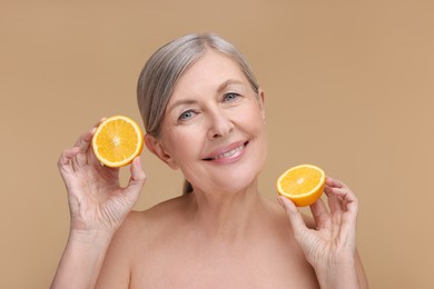Photo of Beautiful woman with halves of orange rich in vitamin C on beige background
