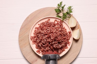 Photo of Manual meat grinder with beef mince, onion and parsley on white wooden table, top view