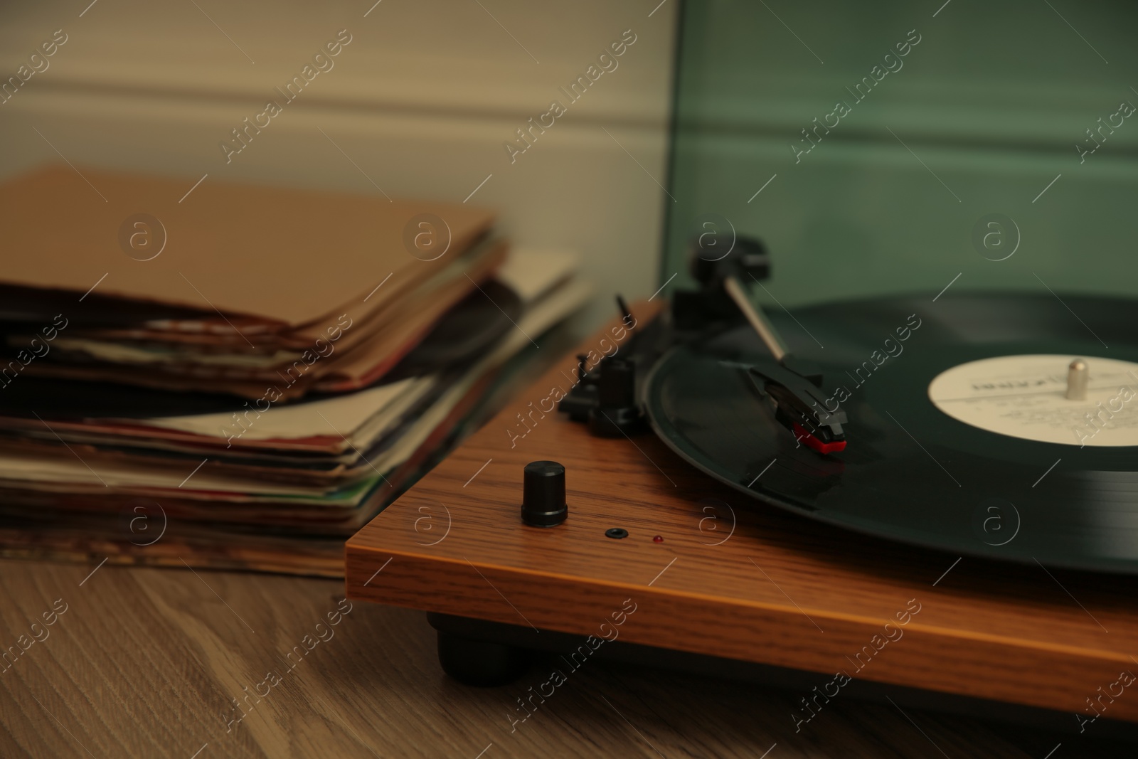 Photo of Stylish turntable and vinyl records on floor indoors, closeup