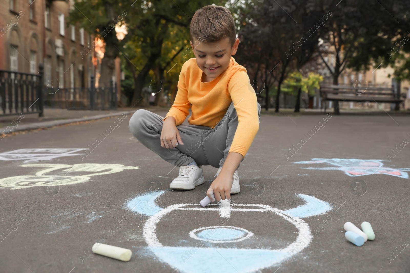 Photo of Child drawing rocket with chalk on asphalt