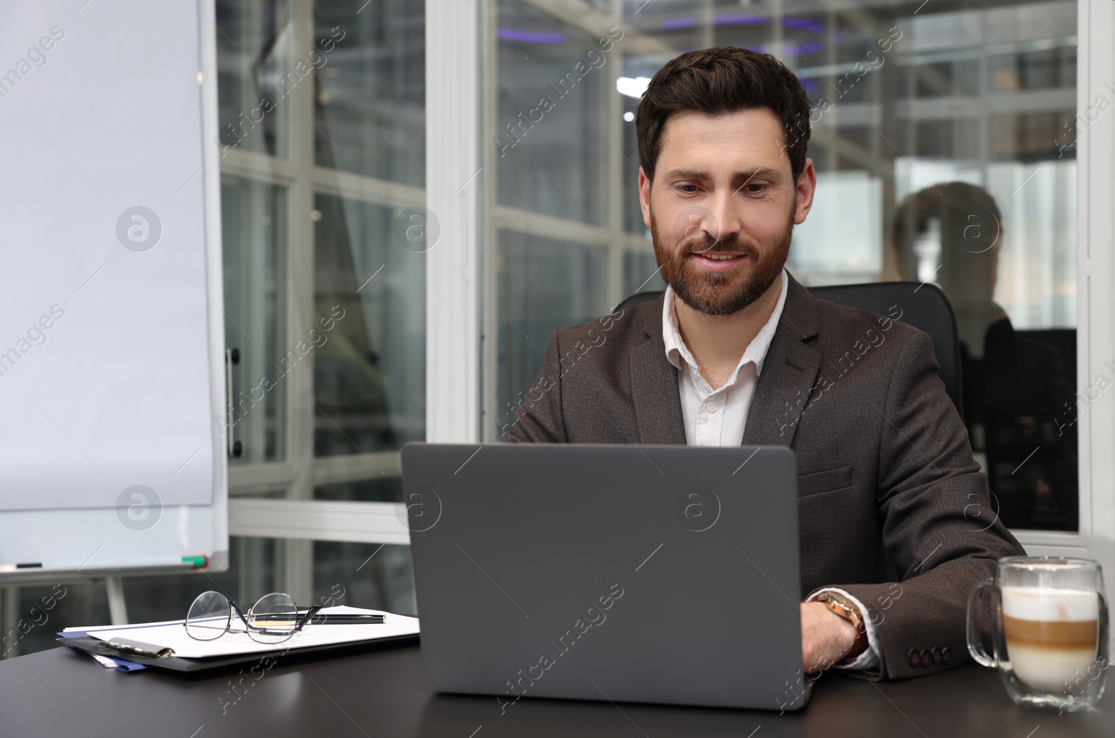 Photo of Man working on laptop at black desk in office