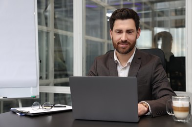 Man working on laptop at black desk in office