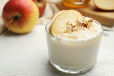 Delicious rice pudding with apple and almond on white wooden table, closeup