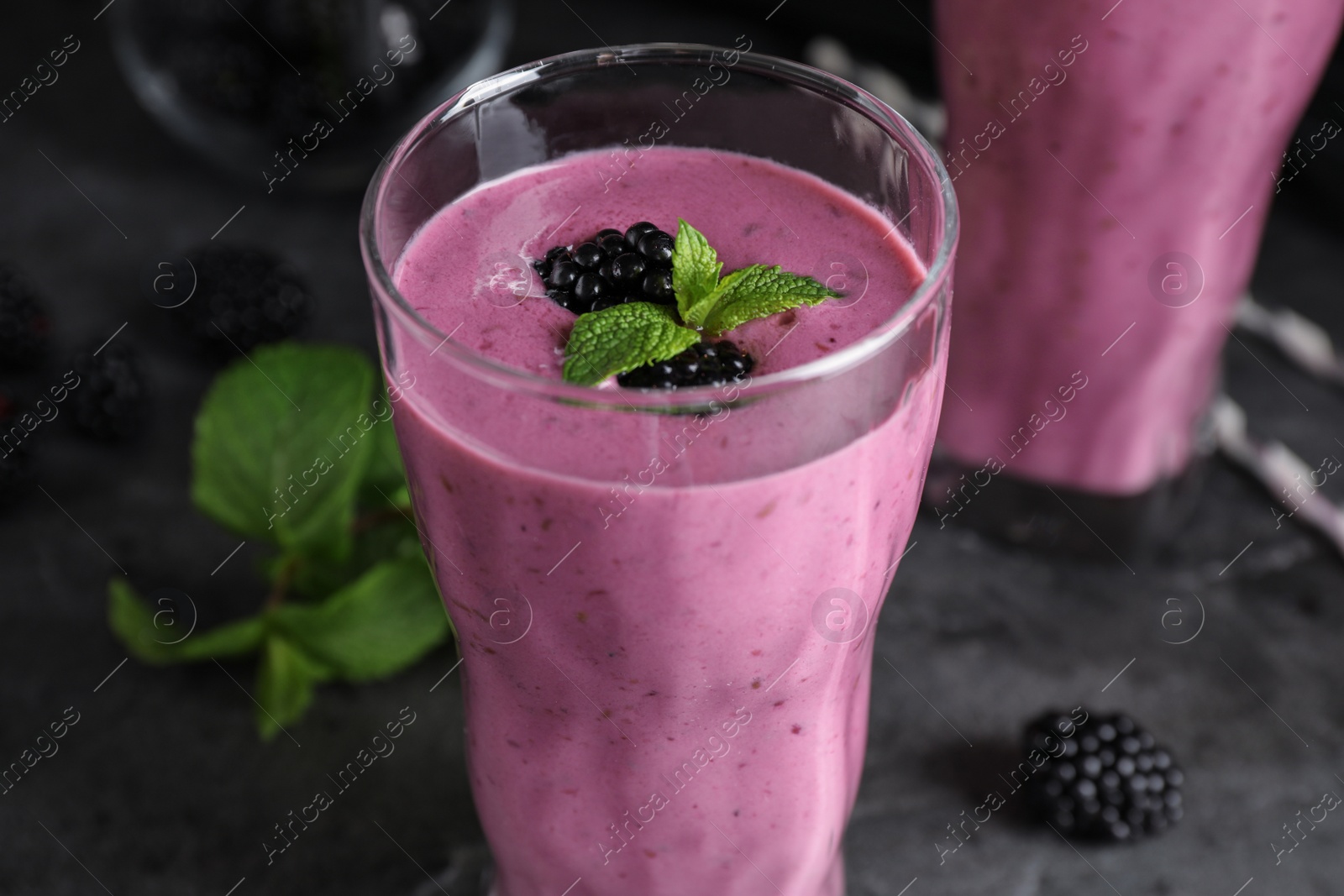 Photo of Glass of tasty blackberry smoothie on grey table, closeup
