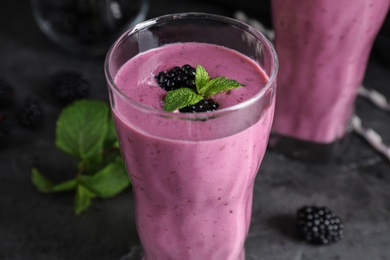 Glass of tasty blackberry smoothie on grey table, closeup