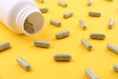 Photo of Jar with vitamin capsules on yellow background, closeup