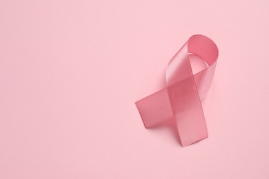 Pink ribbon on color background, top view and space for text. Breast cancer awareness